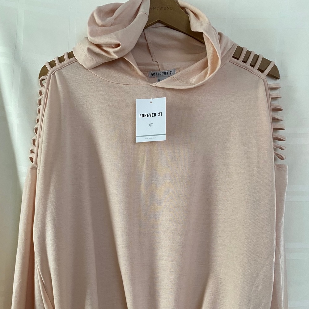Peach hoodie with slits on half the sleeve.